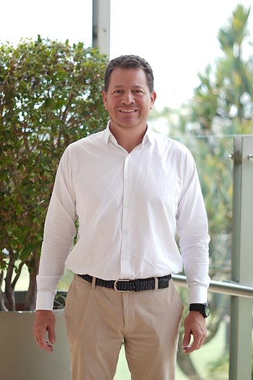 Santiago Molina de pie, sonriendo, con camisa blanca